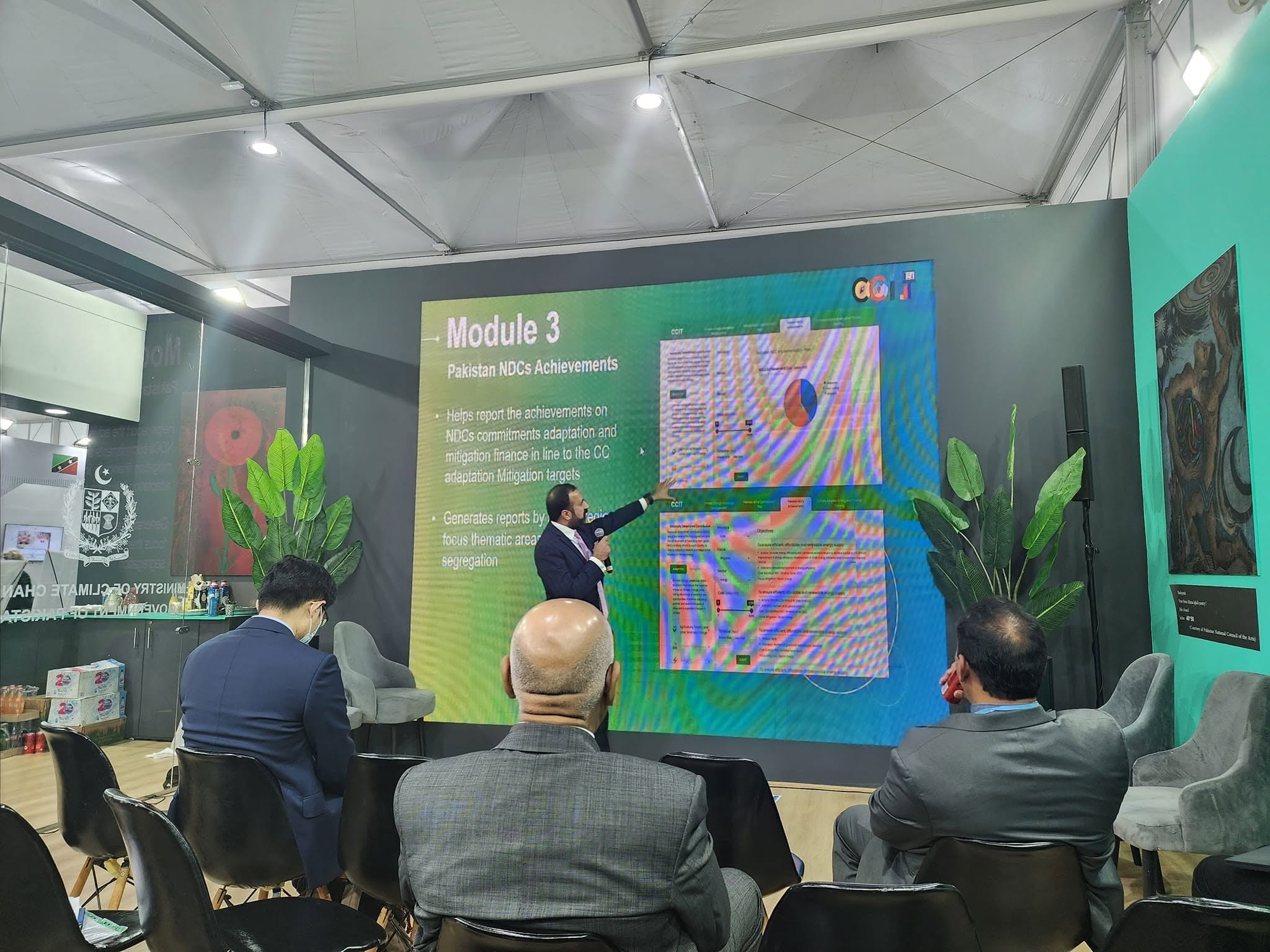 A speaker presenting Pakistan's NDC achievements to a seated audience at the Ministry of Climate Change pavilion, COP27.