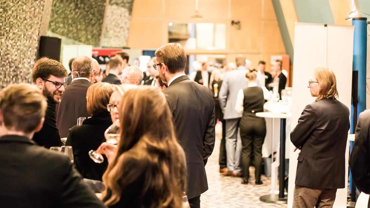 Attendees talking in small groups at a Green Concerns networking event.