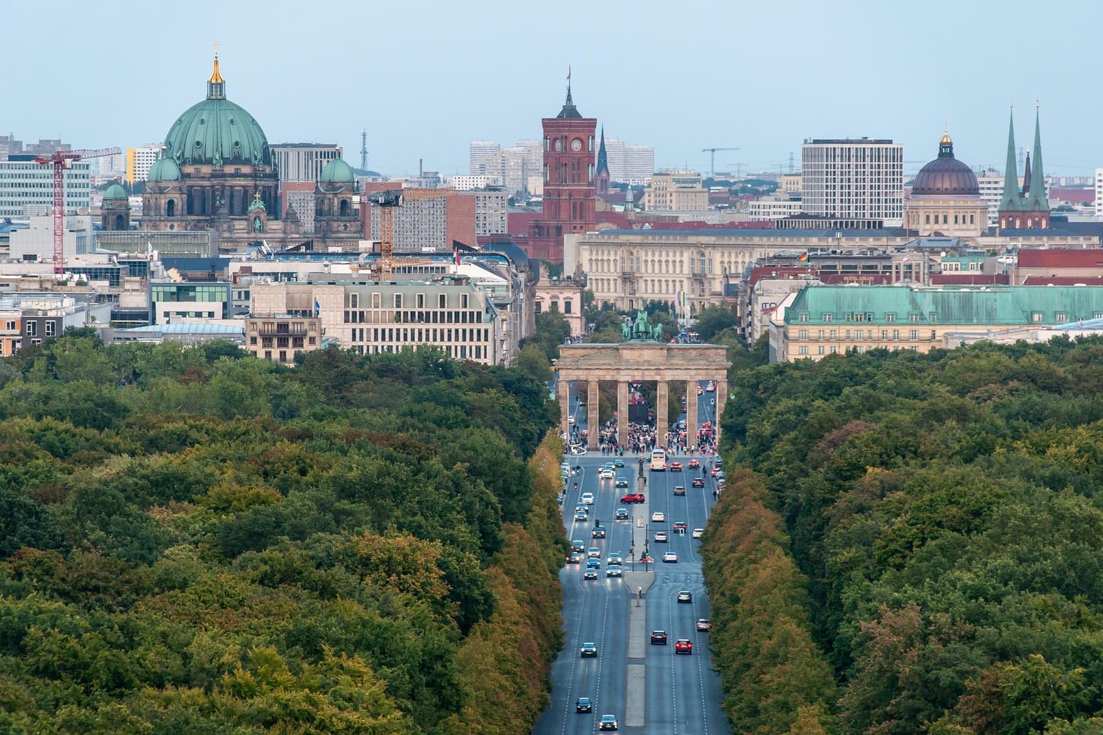 An aerial view of the Brandenburg Gate at the end of a tree-lined avenue in Berlin.