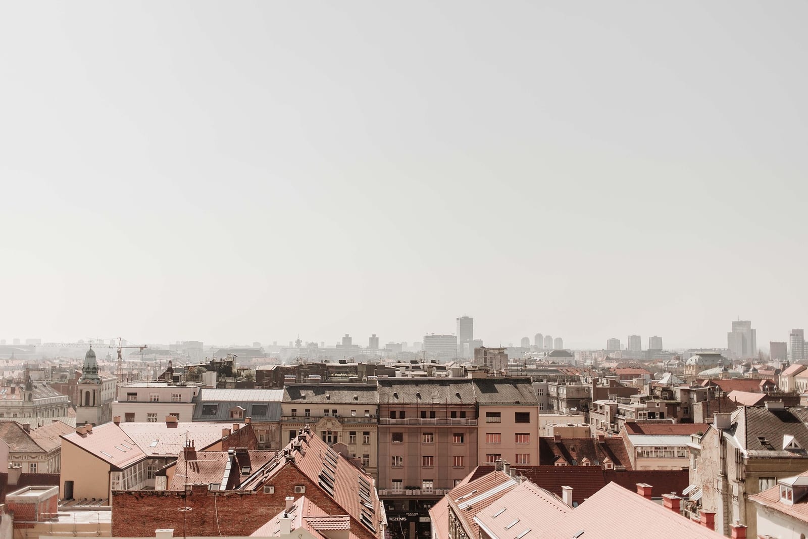 City rooftops receding into haze, with distant towers on the horizon.