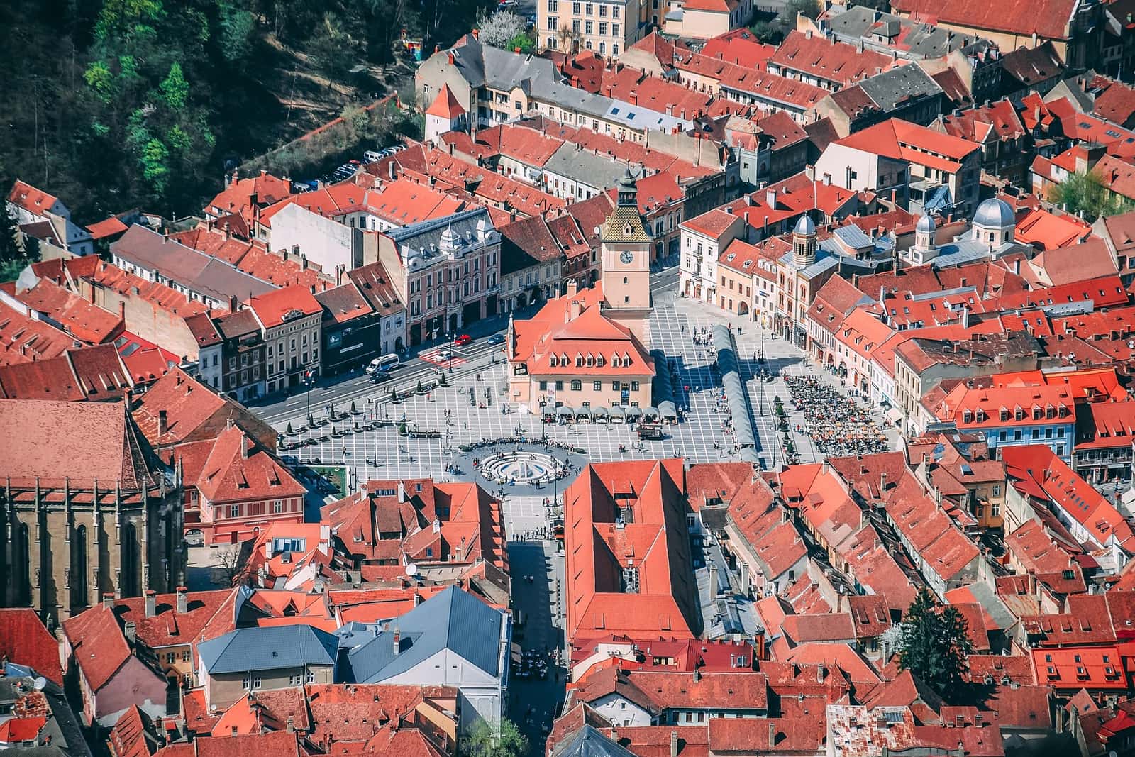 An aerial view of a historic old town, red-tiled roofs gathered around a central square.